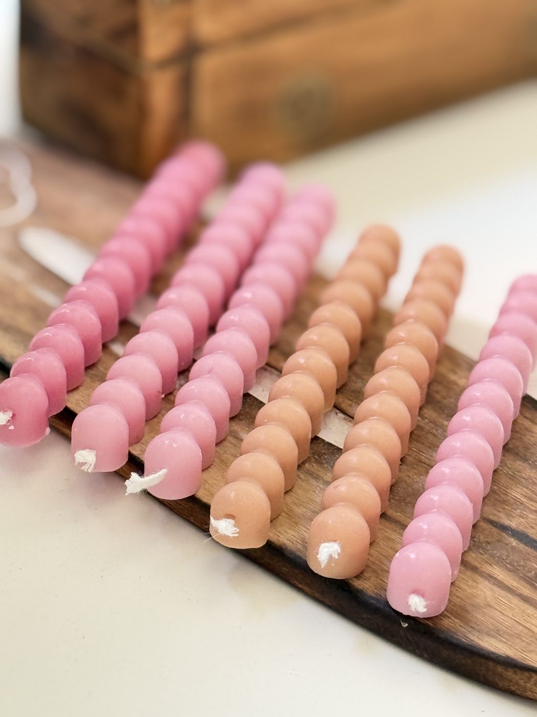 Velas burbuja altas en rosa y melocotón sobre tabla de madera